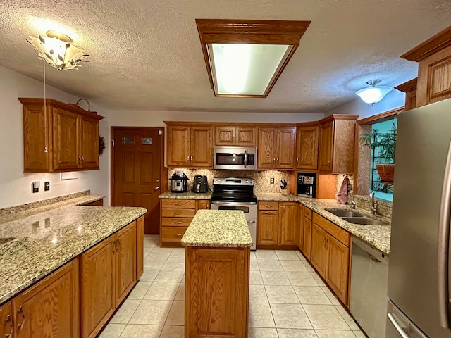 kitchen featuring a textured ceiling, light stone countertops, a center island, stainless steel appliances, and sink