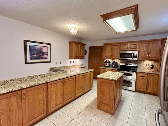 kitchen with a textured ceiling, backsplash, a center island, stainless steel appliances, and light stone counters