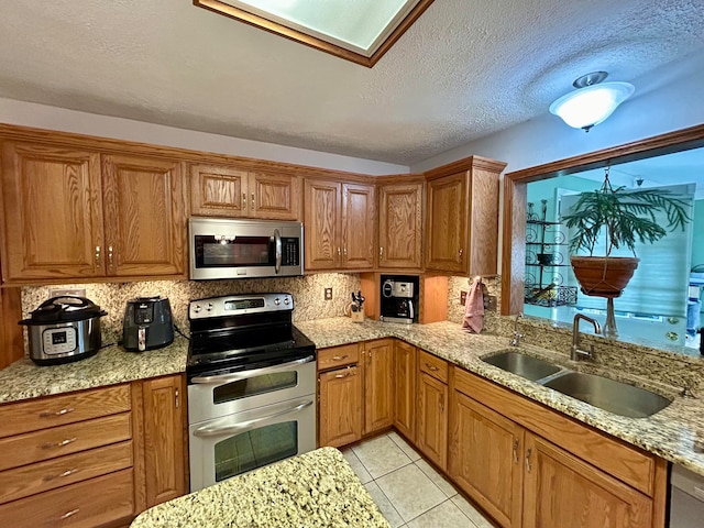 kitchen with sink, appliances with stainless steel finishes, decorative backsplash, and light tile patterned flooring