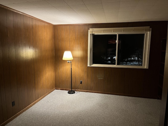 carpeted spare room with wood walls