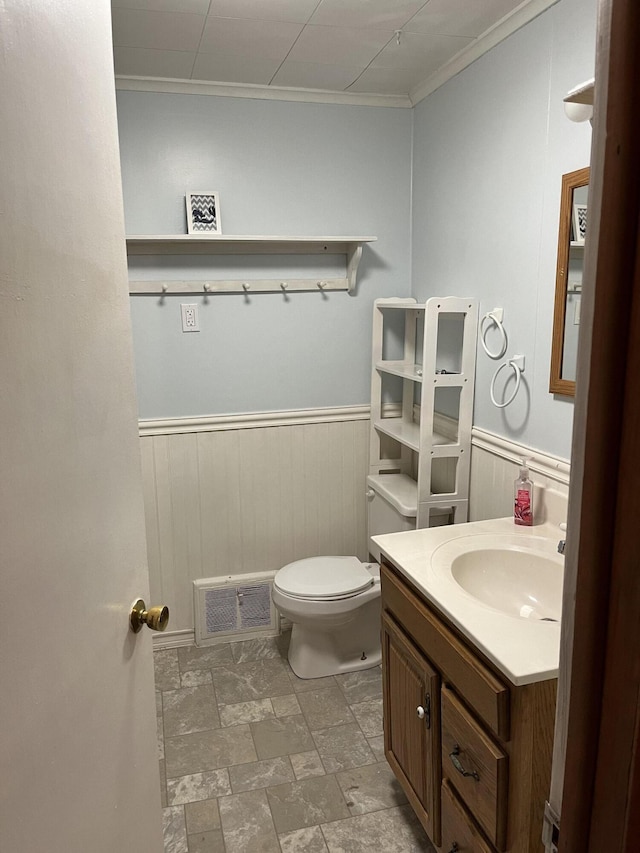 bathroom featuring vanity, wooden walls, crown molding, and toilet