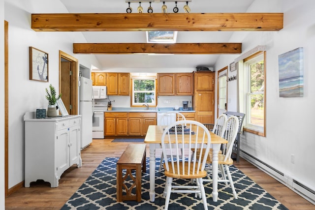 dining room featuring vaulted ceiling with beams, light hardwood / wood-style floors, sink, and a baseboard heating unit