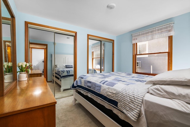 bedroom featuring light carpet and multiple closets