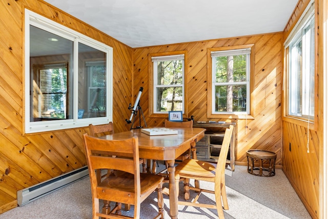 dining space featuring carpet, wooden walls, and a baseboard heating unit