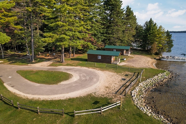 view of property's community featuring a yard, a water view, and an outbuilding