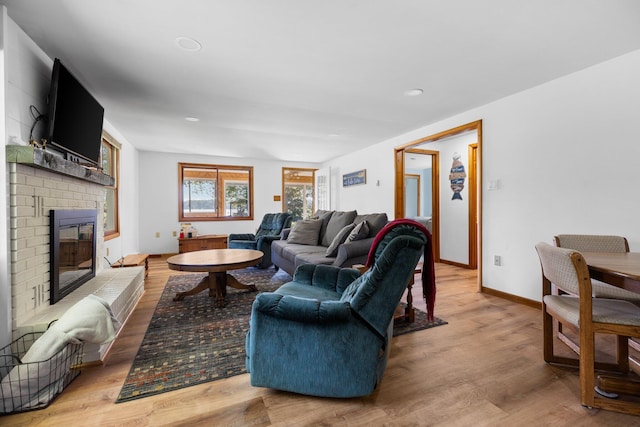 living room featuring light hardwood / wood-style flooring and a brick fireplace