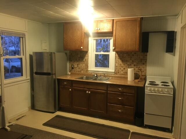 kitchen with stainless steel fridge, sink, tasteful backsplash, and white range oven