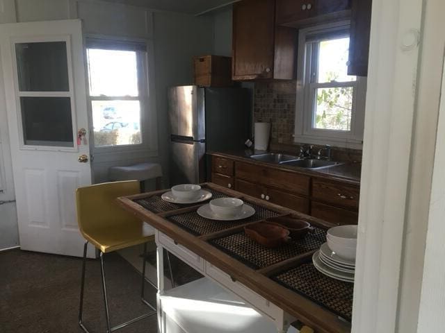 kitchen with stainless steel refrigerator, decorative backsplash, and sink