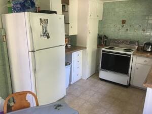 kitchen featuring white cabinets, white appliances, and backsplash