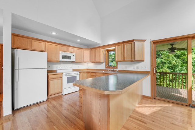 kitchen featuring white appliances, light hardwood / wood-style floors, kitchen peninsula, high vaulted ceiling, and a kitchen bar