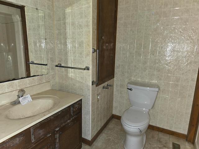 bathroom featuring tile patterned floors, vanity, tile walls, and toilet