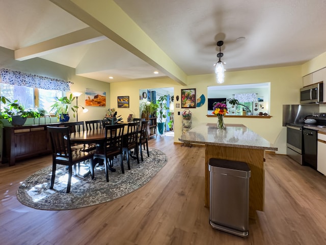 kitchen featuring white cabinets, light stone counters, light hardwood / wood-style floors, stainless steel appliances, and beam ceiling