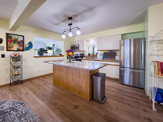 kitchen with light hardwood / wood-style flooring, hanging light fixtures, stainless steel appliances, white cabinets, and a kitchen island