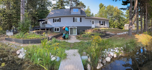 rear view of house featuring a wooden deck and a storage shed