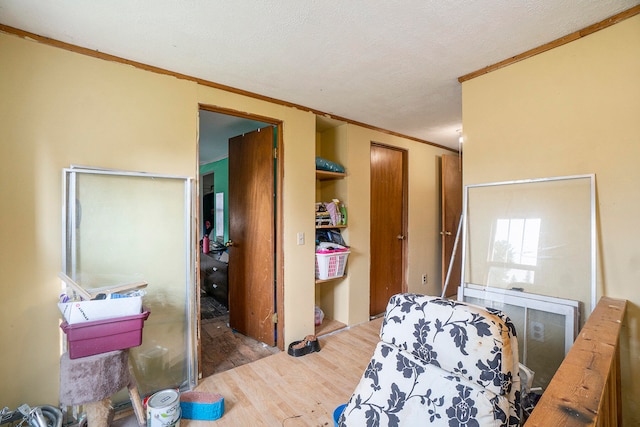 bedroom with hardwood / wood-style floors, a textured ceiling, and ornamental molding