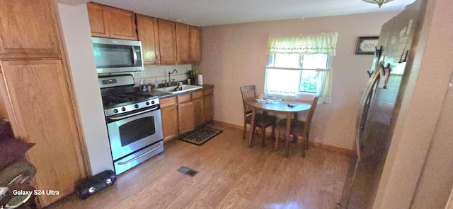 kitchen with appliances with stainless steel finishes, light hardwood / wood-style floors, and sink