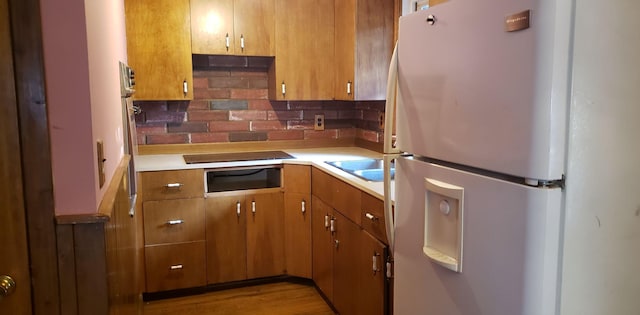 kitchen featuring black electric cooktop, decorative backsplash, light hardwood / wood-style floors, white fridge, and sink