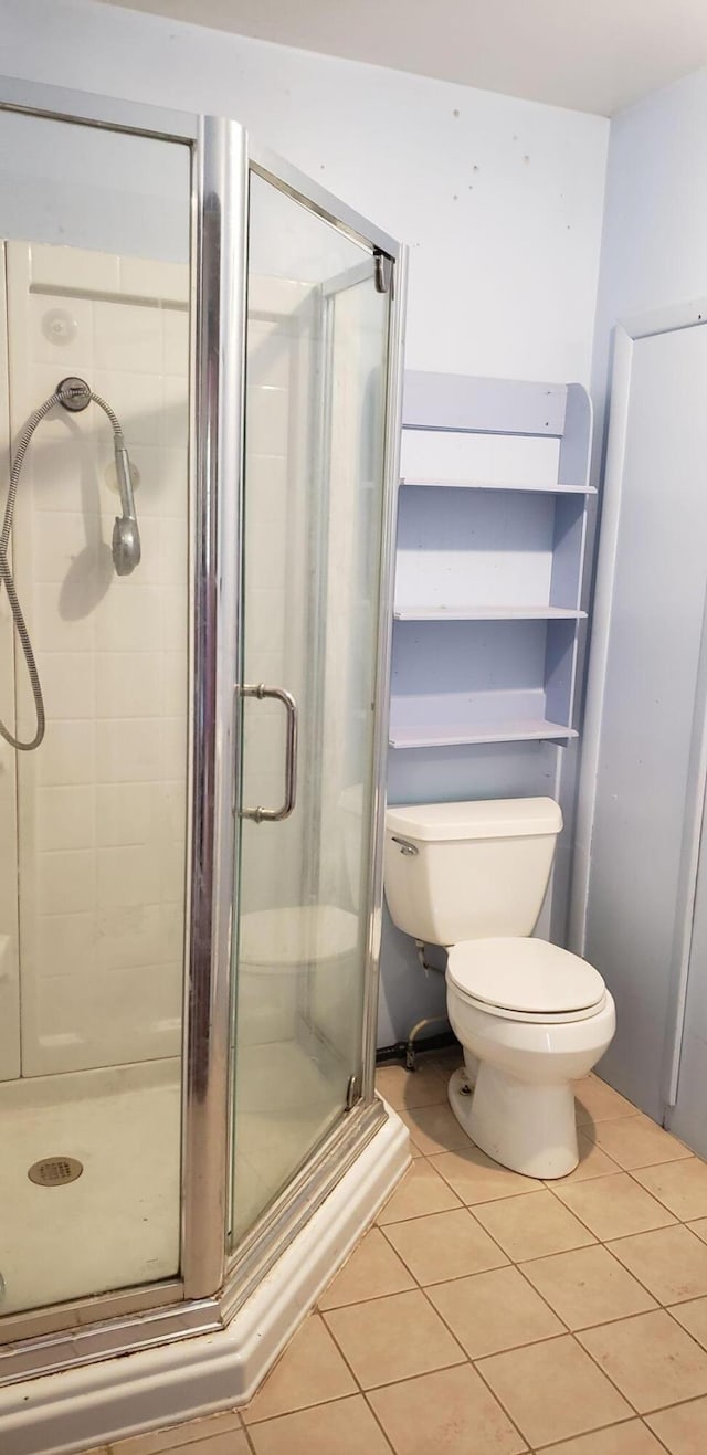 bathroom featuring tile patterned flooring, toilet, and a shower with door