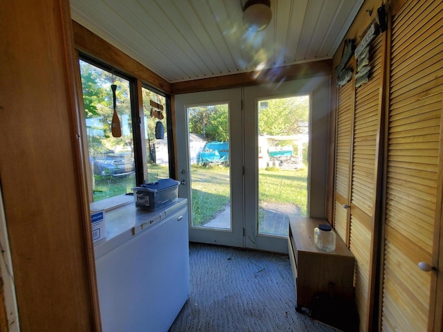 entryway with wooden walls, carpet, wooden ceiling, and a healthy amount of sunlight