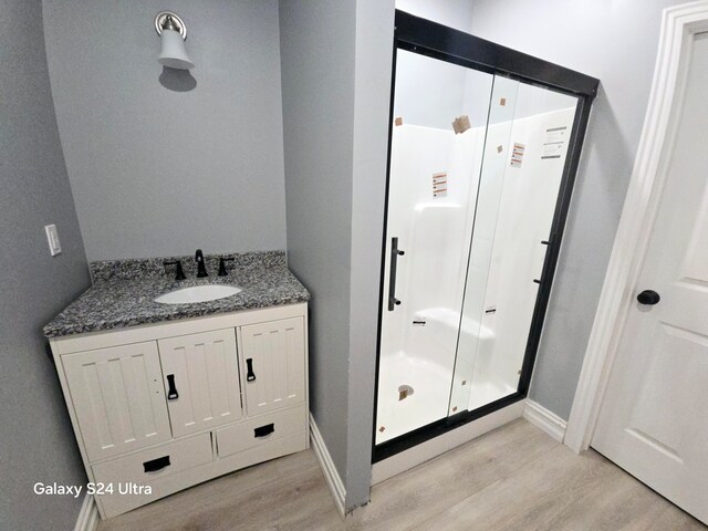 bathroom featuring walk in shower, vanity, and hardwood / wood-style flooring