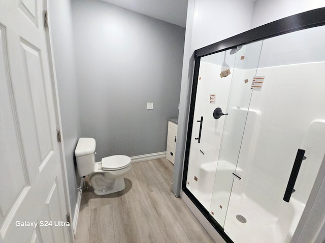 bathroom featuring hardwood / wood-style floors, a shower with door, toilet, and vanity