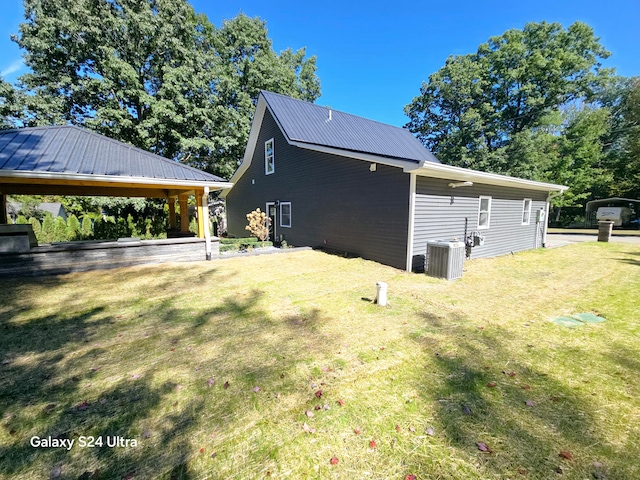 view of side of property featuring a lawn and central AC