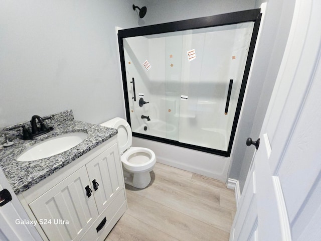 full bathroom featuring vanity, toilet, combined bath / shower with glass door, and hardwood / wood-style flooring