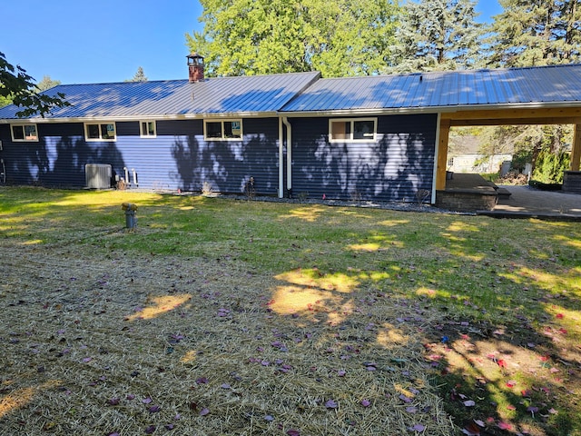 rear view of property with a lawn, central AC unit, and a patio area