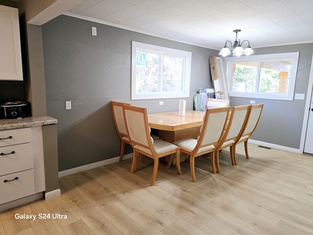 dining space with light hardwood / wood-style flooring, a notable chandelier, plenty of natural light, and ornamental molding