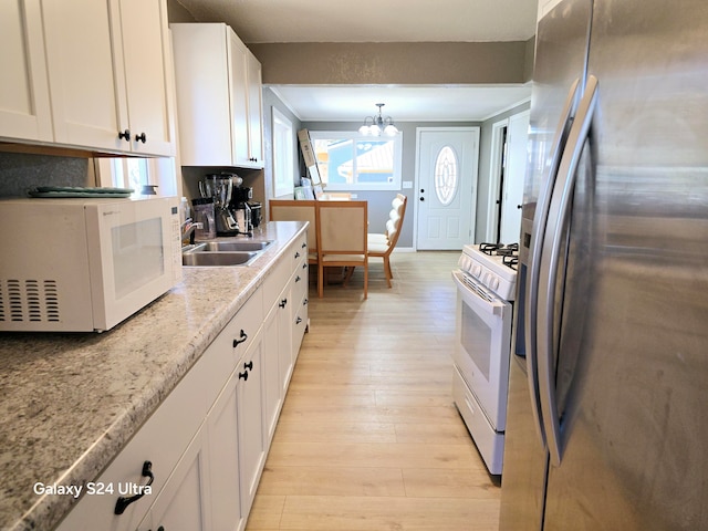 kitchen featuring white cabinetry, white appliances, light hardwood / wood-style flooring, sink, and a notable chandelier