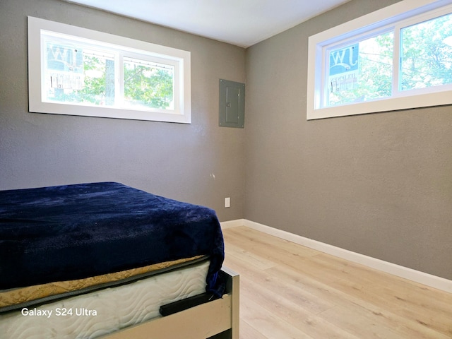 bedroom featuring multiple windows, hardwood / wood-style floors, and electric panel