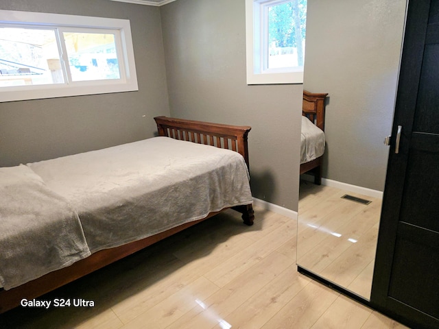 bedroom with light hardwood / wood-style floors and multiple windows