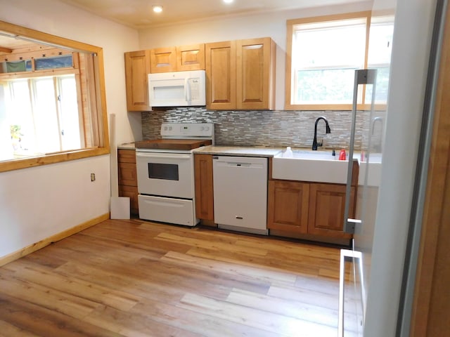 kitchen with light wood-type flooring, white appliances, backsplash, and sink