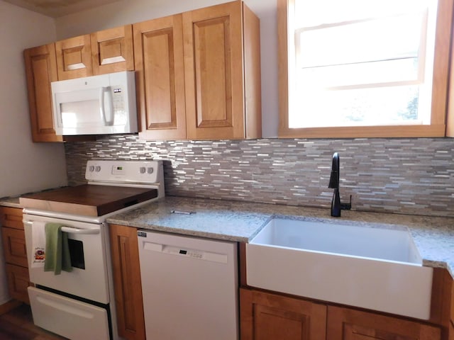 kitchen featuring decorative backsplash, sink, light stone counters, and white appliances