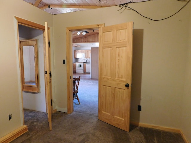 hallway featuring vaulted ceiling, dark carpet, and wooden ceiling