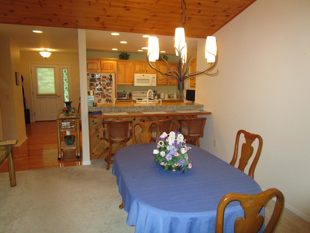 carpeted dining room with a notable chandelier, wood ceiling, and sink