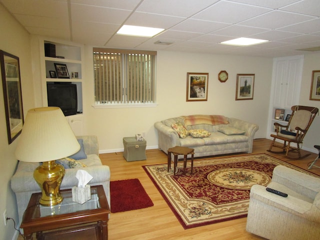 living room with a drop ceiling and hardwood / wood-style floors