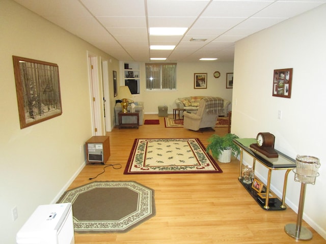 hall with a paneled ceiling and hardwood / wood-style flooring