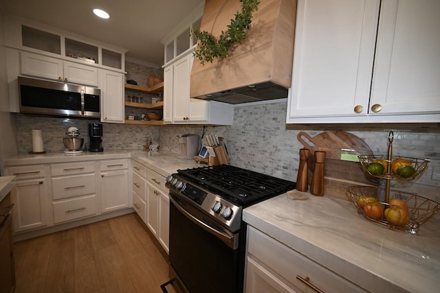 kitchen with black gas stove, backsplash, custom exhaust hood, and white cabinets