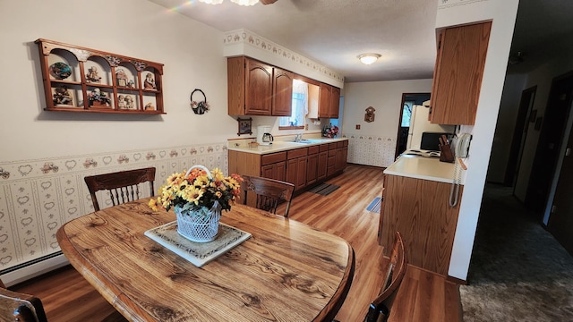 dining space featuring wood-type flooring, baseboard heating, and sink