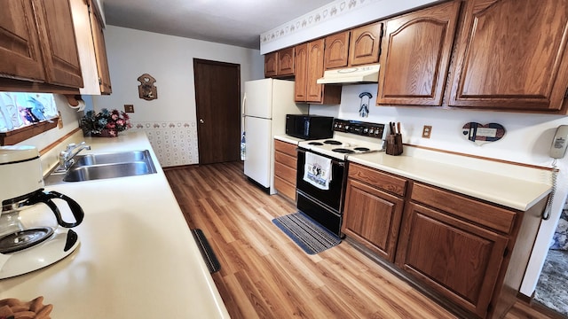 kitchen with light wood-type flooring, sink, and white appliances