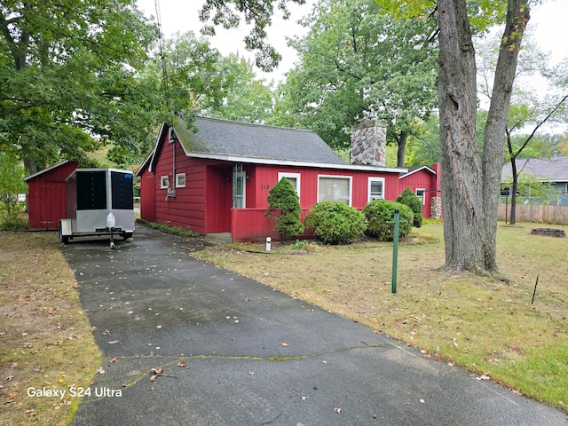 view of front of home featuring a front lawn and a shed