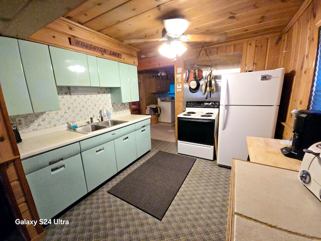 kitchen with washer / clothes dryer, white appliances, ceiling fan, wooden walls, and sink