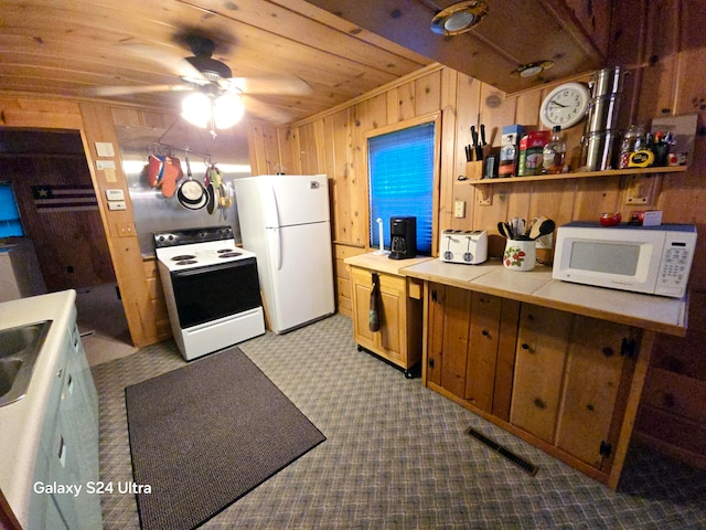 kitchen with ceiling fan, wood ceiling, wood walls, white appliances, and tile countertops