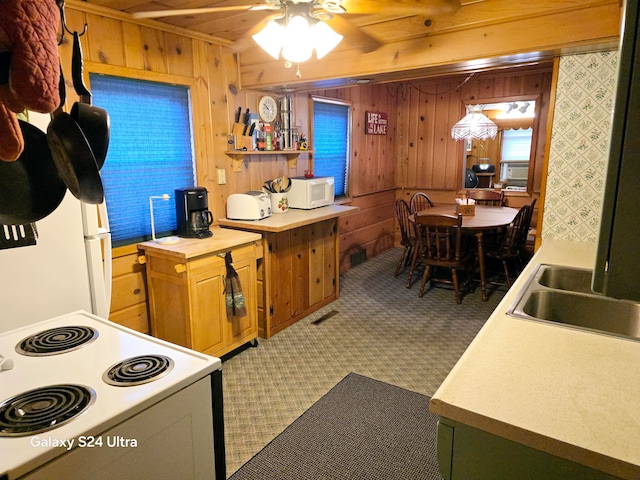 kitchen with wooden walls, white appliances, ceiling fan, and cooling unit