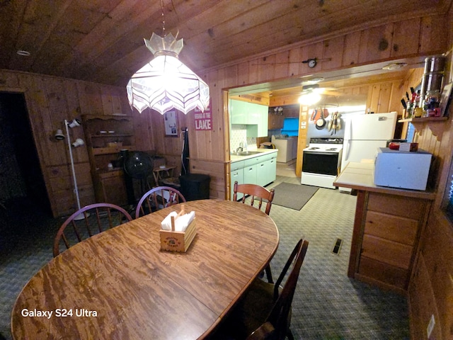 carpeted dining space with wood ceiling, wood walls, vaulted ceiling, and sink