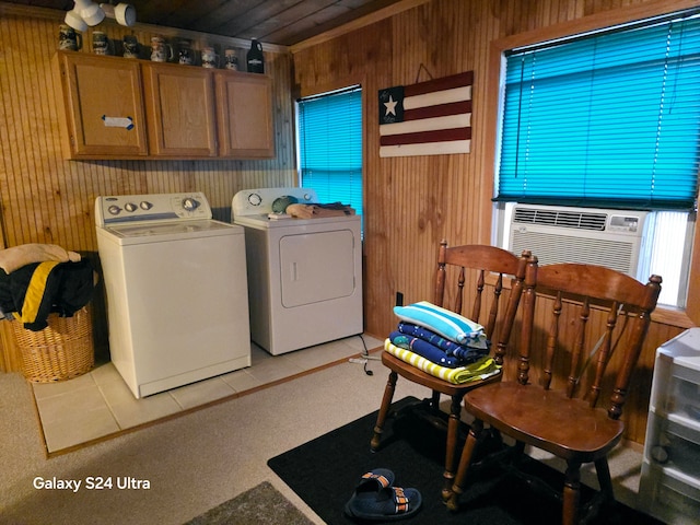 clothes washing area with cooling unit, light tile patterned flooring, wooden walls, cabinets, and independent washer and dryer