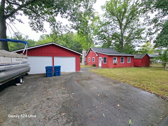 ranch-style home featuring a garage, a front yard, and an outbuilding