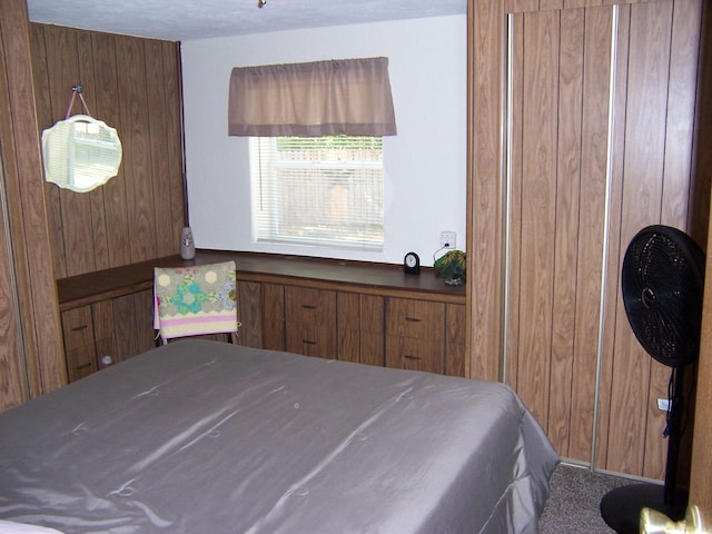 bedroom with a textured ceiling, carpet, and wood walls