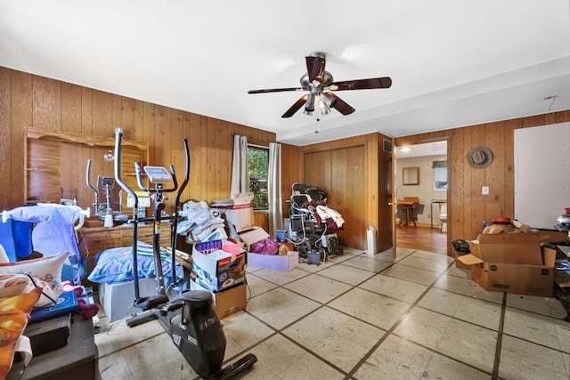 interior space featuring ceiling fan and wooden walls